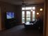 Cozy living room with elegant decor, featuring a leather chaise lounge, stylish floor lamp, and a large window offering natural light.