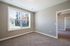 Bright, spacious room with plush carpeting and a large window offering scenic views, perfect for effortless living.
