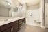 Luxurious bathroom featuring a spacious walk-in shower, dual sinks with sleek dark wood cabinetry, and elegant lighting.