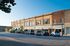 Charming, sunlit street view of historic brick building with large windows, ideal for commercial opportunities.