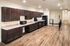 Modern kitchen featuring dark wood cabinetry, sleek countertops, and stainless steel appliances, with stylish hardwood flooring.