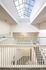 Bright and airy apartment hallway featuring a modern skylight and elegant white railings.