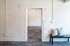 Inviting apartment entryway featuring textured walls, a cozy bench with stylish cushions, and contemporary flooring.
