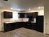Modern kitchen with elegant dark wood cabinetry, sleek black appliances, and ample counter space, perfect for culinary creations.