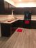 Modern kitchen with sleek dark cabinets, stylish countertops, and elegant wood flooring, complete with vibrant red accents.