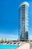 Modern cylindrical high-rise with glass fa&ccedil;ade featuring a luxurious rooftop pool and sunbeds under a clear blue sky.