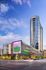 Modern skyscraper with sleek architecture featuring a vibrant Whole Foods Market at its base, set against a stunning blue sky.