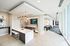 Modern open-plan apartment with sleek kitchen, stylish bar seating, ambient lighting, and a vibrant lounge area.
