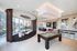Luxurious apartment interior featuring a modern open-concept dining area, pool table, and floor-to-ceiling windows with stunning city views.