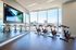 Modern gym with stationary bikes and a scenic city view, featuring a large screen for virtual cycling experiences.