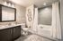Elegant bathroom featuring a modern vanity with dark wood cabinets, large mirror, and luxurious bathtub with sleek tile design.