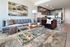 Chic and modern living room featuring a plush gray sofa, elegant glass coffee table, vibrant abstract artwork, and a sleek open kitchen design.