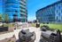 Chic outdoor lounge area with modern patio furniture and built-in BBQ, set against a backdrop of contemporary glass apartment buildings.
