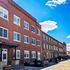 Charming red-brick apartment building with modern windows basking under a bright blue sky, offering spacious and stylish urban living.
