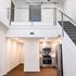 Modern loft apartment with sleek stainless steel kitchen appliances, open staircase, and chic railing design.