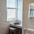 Charming apartment nook featuring a stylish window seat with a brick accent wall, modern bar setup, and cozy gray stool.