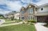 Charming townhouse with beautiful stone fa&ccedil;ade and lush landscaping under a bright blue sky.