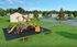 Vibrant community park with colorful playground, lush greenery, and charming residential homes in the background.