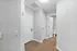 Modern entryway featuring sleek hardwood flooring and crisp white doors leading to a bathroom, radiating elegance and style.