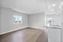 Bright and modern open-concept living area with sleek hardwood floors, large windows, and a contemporary kitchen counter.