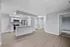 Modern open-plan kitchen with sleek stainless steel appliances, granite countertops, and elegant wood flooring extending into the bright living area.