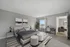 Elegant bedroom with modern decor, featuring a plush bed, contemporary artwork, and a cozy seating area near a bright window.