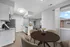 Modern open-concept kitchen and dining area with natural light, sleek white cabinets, granite countertops, and wood flooring.