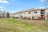 Charming apartment complex with inviting entrances, manicured lawns, and serene surroundings under a bright blue sky.