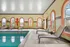 Inviting indoor swimming pool area with elegant loungers and vibrant arched windows, perfect for relaxation.