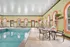 Inviting indoor pool area with modern lounge chairs, elegant arched windows, and lush greenery, perfect for relaxation.