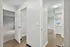 Bright, open corridor leading to a cozy bedroom with plush carpeting, alongside a stylish kitchen with modern fixtures and wood flooring.