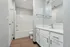 Modern bathroom featuring pristine white fixtures, sleek cabinetry, and elegant wood flooring with a spacious shower area.