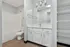 Modern bathroom with sleek white cabinetry, spacious vanity, and ample shelving. Complemented by stylish lighting and a classic bathtub-shower combination.