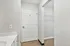Bright, airy hallway with modern white door and spacious closet, featuring sleek wooden flooring.