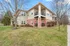 Charming two-story brick and siding apartment with private balconies, set amidst lush green lawns and mature trees.