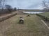 Expansive outdoor space featuring a fenced grassy area with agility equipment, perfect for pet exercise, with scenic water views in the background.
