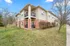 Charming two-story apartment building with red brick accents and inviting balconies, surrounded by lush green lawns and trees.