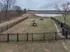 Expansive fenced dog park featuring agility equipment and scenic views by a tranquil pond.