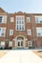 Charming red brick apartment building with elegant arched entrance and large windows, offering a blend of classic architecture and modern living.
