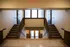 Elegant interior staircase with dual sets of stairs, large frosted windows, and inviting doors leading to bright spaces.