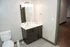 Modern bathroom with sleek dark wood vanity, elegant lighting, and a spacious mirror for a stylish touch.