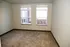 Bright and inviting room with large windows offering natural light and cozy carpeting, perfect for personalization.