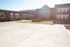 Modern educational building with a spacious concrete courtyard and inviting entrance, featuring large windows for ample natural light.