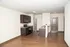 Modern apartment kitchen with elegant dark wood cabinets and sleek countertops, adjacent to an inviting open living space with natural light.
