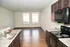 Bright, open-concept kitchen and living space with dark wood cabinetry, large windows, and sleek appliances.