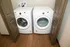 Modern laundry area featuring an efficient front-loading washer and dryer set, enclosed by stylish double doors on polished wood flooring.