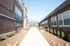 Charming entrance walkway flanked by beautifully landscaped gardens and classic brick architecture, leading to modern apartments.
