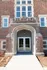 Charming brick building entrance with elegant stone archway and large windows, showcasing classic architectural style.