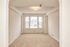Bright and inviting room with large windows, neutral carpet, and elegant archway detail, perfect for a cozy living space.