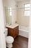 Elegant bathroom with rich wood cabinetry, modern white fixtures, and sleek dark wood flooring.